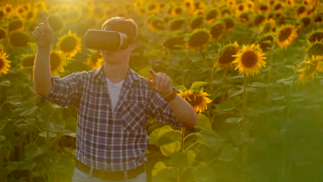 The-young-man-is-working-in-VR-glasses.-He-is-engaged-in-the-working-process.-It-is-a-beautiful-sunny-day-in-the-sunflower-field